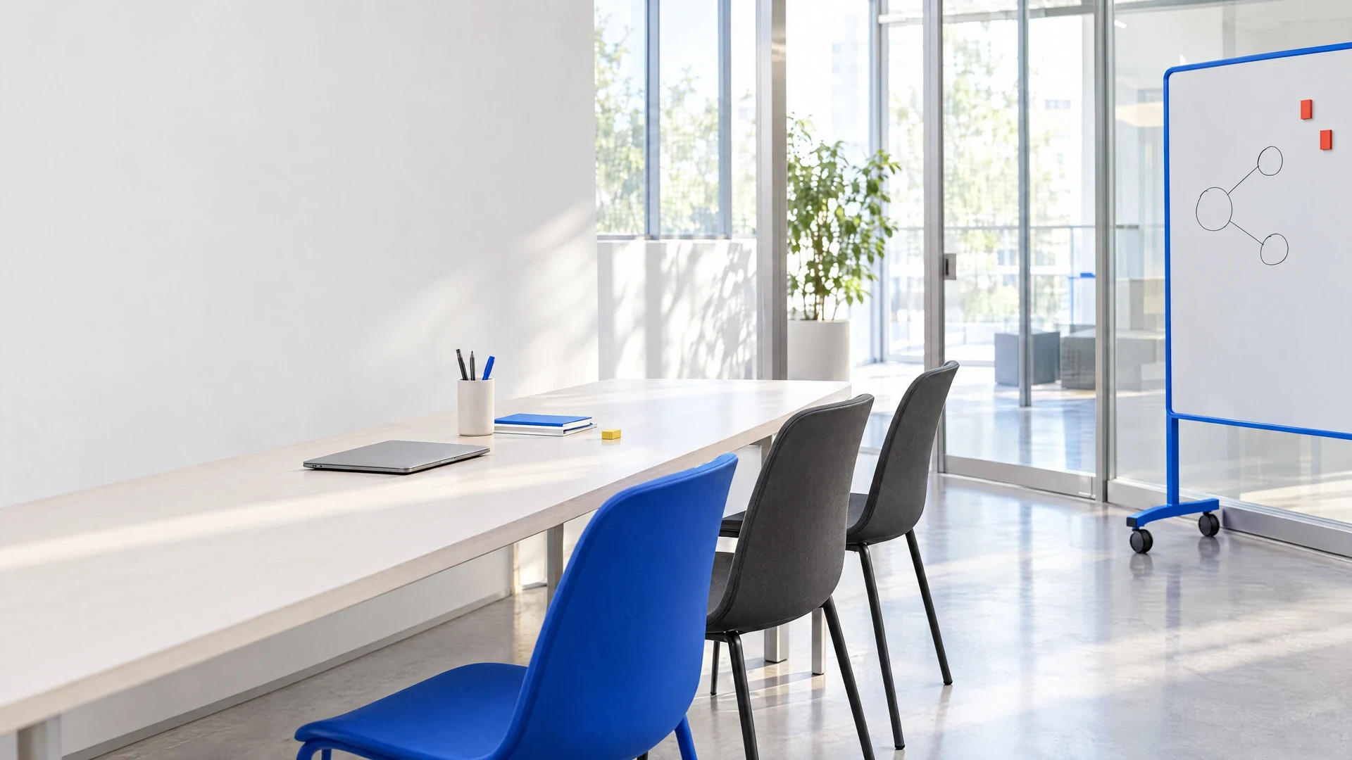 Conceptual architectural photograph of an empty shared learning studio with a working table, chairs and a whiteboard.